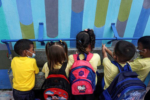 Un grupo de niños se lavan las manos en un grifo múltiple que suministra agua de lluvia filtrada en el preescolar Fermín Toro, beneficiario del programa "Lata de Agua", en el populoso barrio de Petare en Caracas